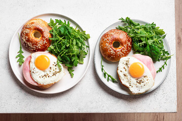 Healthy breakfast. Bagels with fried egg, ham and greens