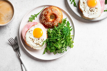 Healthy breakfast. Bagels with fried egg, ham and greens