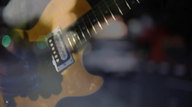 Electric guitar closeup hand entering and picking strings changing chords to play under bokeh