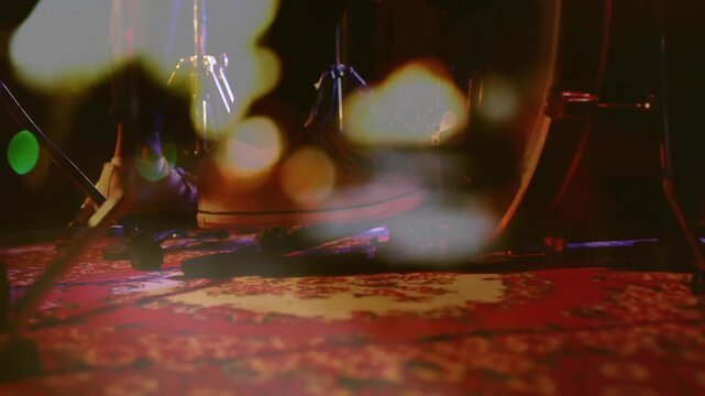 Male drummer shifting foot and adjusting drum pedal for music set while bokeh drifting over rug