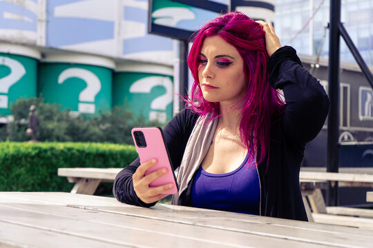 Woman with magenta hair using smartphone outdoors - Powered by Adobe