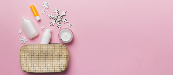 Christmas flat lay with makeup cosmetic products in cosmetic bag on colored background. Top view New year Beauty concept