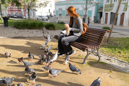 Woman feeding pigeons in urban city park