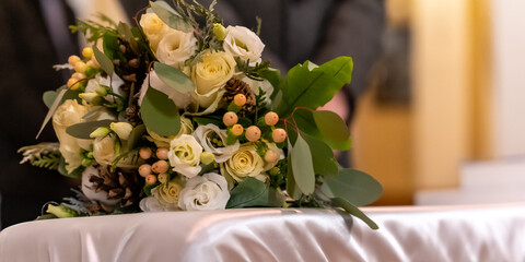 Rustic White Rose Wedding Bouquet Placed On Table Before Ceremony With Greenery And Pine Cones