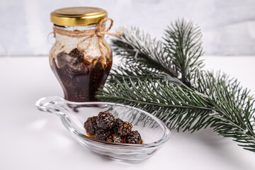 Homemade medicinal cone jam in a jar with a sprig of fir on a white background