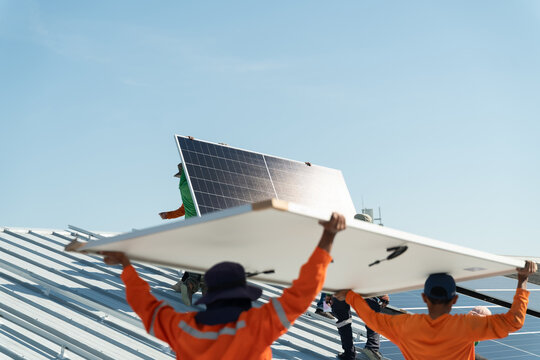 Workers install solar panels on a rooftop in bright sunlight during a clear day in a bustling urban area