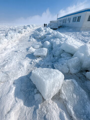 Icy landscape with snow chunks near a building in winter.