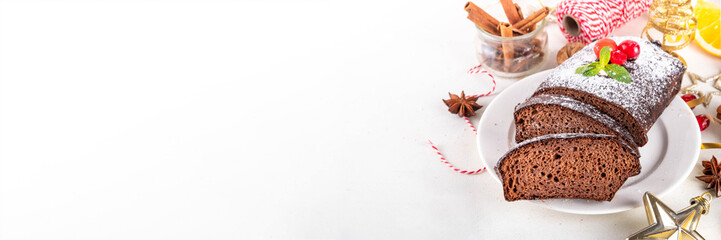 Homemade gingerbread loaf cake. Freshly baked Christmas Gingerbread chocolate cake with sugar powder topping, on white festive decorated background