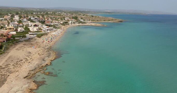 Aerial view of the sandy beach of San Lorenzo, located in the province of Syracuse, Sicily, Italy. It is a popular summer resort. There are parasols and vacationers on this coast with clear waters.