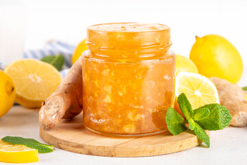 Ginger lemon jam marmalade preserves in small jar with fresh ginger, lemons and mint, on white table copy space