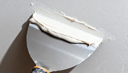 Closeup medium shot of lightweight joint compound being spread evenly with a putty knife emphasizing ease of use and smooth surface finishing in drywall installation.