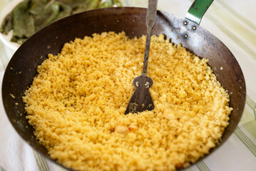 Close-up of traditional Granada style flour migas in a rustic pan served on a home dining table