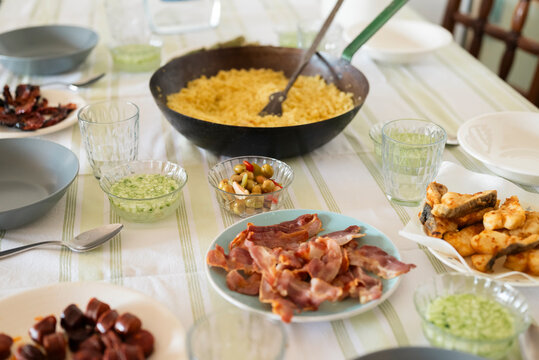 Traditional Granada-tyle flour migas served in a rustic pan with typical accompaniments like panceta, chorizo, fish and cucumber gazpacho on a home dining table