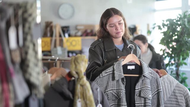  young woman chooses different winter clothes in a clothing store. High quality 4k footage