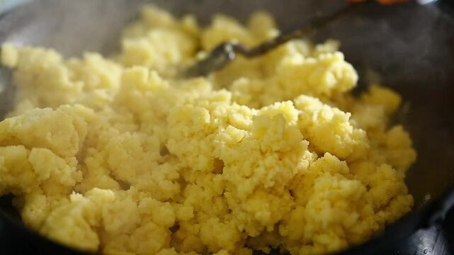 Close-up of traditional Granada-style flour migas being cooked in a rustic pan with a metal rasera