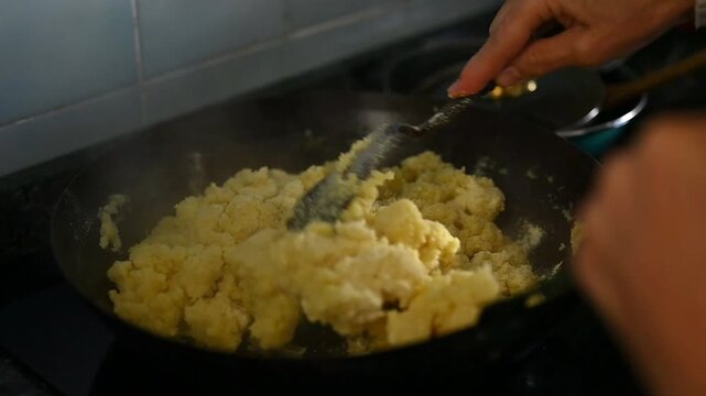 Traditional Spanish migas in a rustic pan with flour being added and stirred by hand