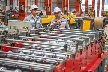 Engineers inspecting equipment and discussing maintenance procedures inside a modern industrial factory. Safety, teamwork, and production quality control in a manufacturing plant.