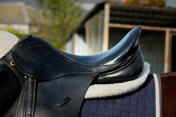 Close up of a sport horse saddle. Quality classical leather saddle ready for horse workout. Equestrian sport background outdoors