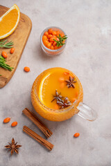 Fototapeta premium Sea buckthorn herbal tea in a cup on a light background with orange, spices and berries.