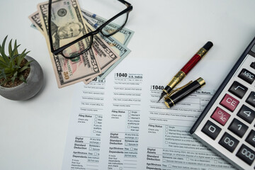 Form 1040 with US dollar bills, glasses and calculator for 2025 tax filing