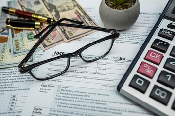 Close up of 1040 form with scattered US dollars, glasses and pen — 2025 tax documents