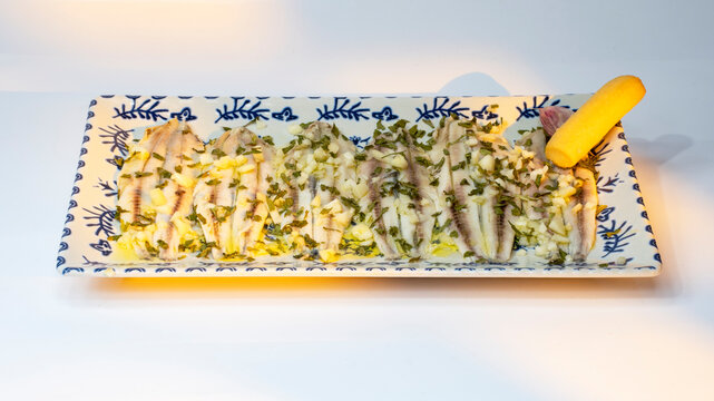 boquerones en vinagre con aceite de oliva ajo y perejil en una bandeja de porcelana decorada