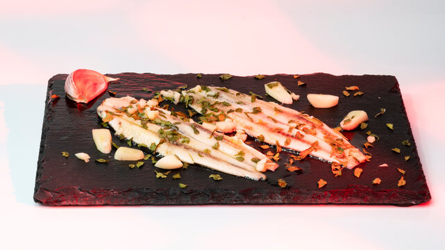 boquerones en vinagre con aceite de oliva ajo y perejil en un plato de pizarra negro