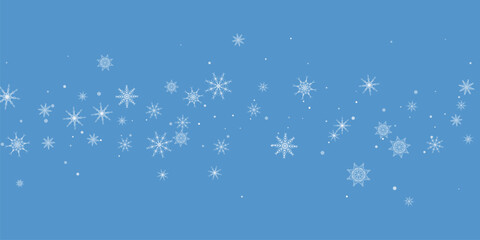 White delicate, lacy snowflakes are carried by the wind against a blue background. Christmas or New Year's