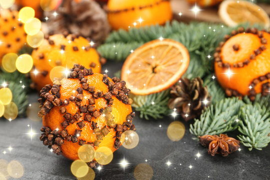 Fresh tangerines decorated with cloves (Pomander balls) and fir tree branches on table, bokeh lights