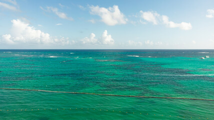 Vista aérea de una playa de arena blanca con palmeras, yates, barcos, océano azul y cielo azul al...