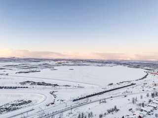 Iron ore freight train near Kiruna Iron Ore mine, during arctic winter, wind power plant in the distance, high mountain peaks. Sweden