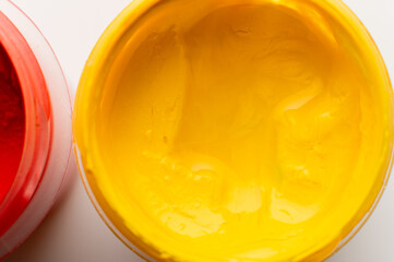 close-up shot of thick, bright yellow paint in a plastic jar. Gouache paint set. Jars of gouache are painted on a white background