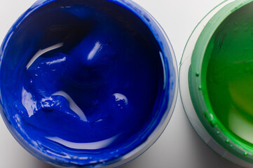 Bright blue paint, macro shot of gouache paint texture. Open paint on a white table, a drawing and creative tool
