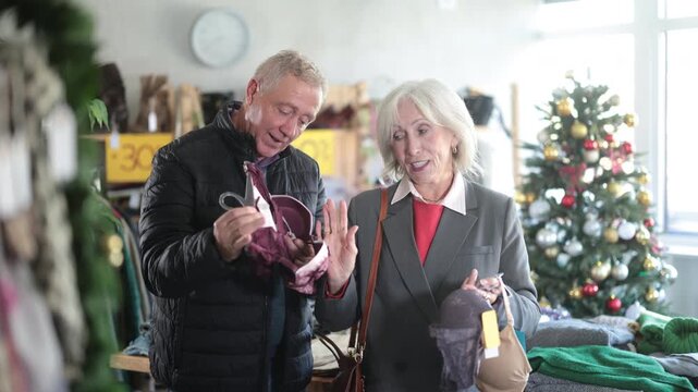 Uncertain mature man and woman choosing some bra in clothing store during Christmas sale. High quality 4k footage