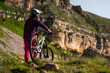 Man riding a mountain bike on a dirt road for an adrenaline rush, fitness, or extreme outdoor sport. A man cyclist or biker riding for stunts