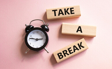 Take a break symbol. Concept words Take a break on wooden blocks. Beautiful pink background with alarm clock. Business and Take a break concept. Copy space.