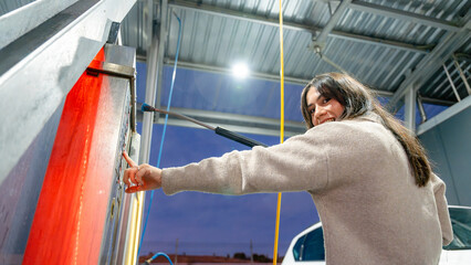 Woman using pressure washer at self-service car wash
