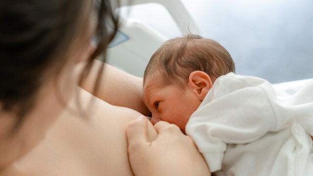 Mother breastfeeding newborn in a comforting embrace