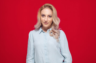 Portrait of beautiful woman, isolated on red background. Pretty blond girl looking at camera