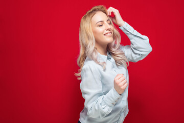 Party girl with closed eyes dancing, isolated on red background. Playful young woman at amusing concept