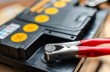 Charging a car battery with a red jumper cable clamp