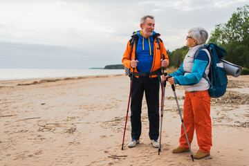 Hiking tourism adventure. Senior couple man woman enjoying outdoor recreation hiking on beach. Happy old people backpackers hikers enjoy walking hike trekking tourism active vacation beauty of nature