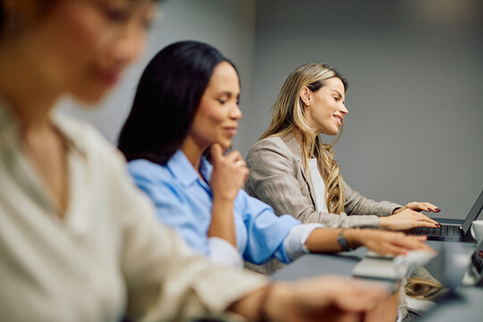 Group of diverse businesswomen attending a corporate seminar, learning and networking while using laptops