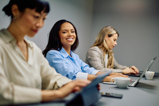 Diverse businesswomen attending a corporate meeting, collaborating and using digital devices in a modern office environment - Powered by Adobe