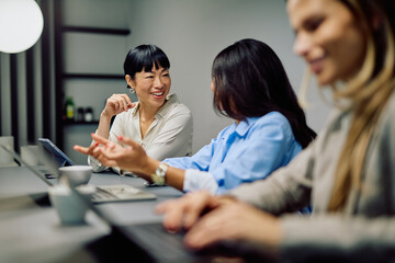 Multi-ethnic businesswomen discussing ideas during a meeting. Professionals actively working and smiling together in a modern office