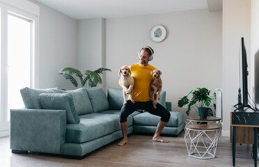 Man exercising at home while holding playful pets