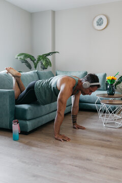 Man exercising at home on sofa in bright living room