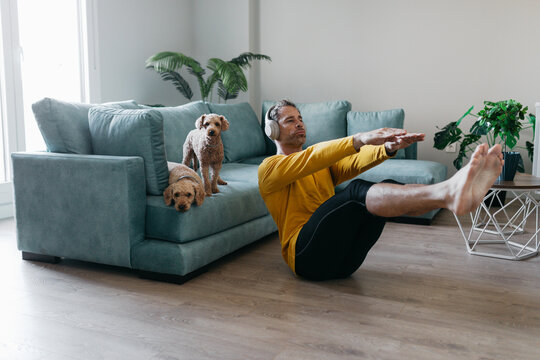 Man practicing sit ups at home with dogs nearby