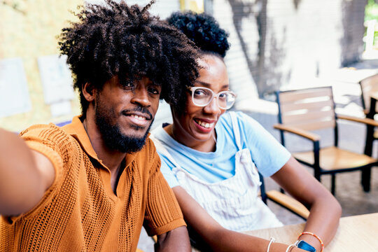 Smiling couple taking a selfie in a cafe setting - Powered by Adobe