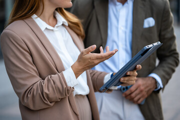 Businesswoman gesturing while discussing work with male colleague using tablet